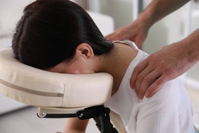 Photo of Woman receiving massage in modern chair indoors, closeup