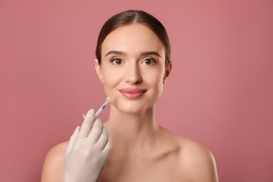 Photo of Beautiful woman getting facial injection on pink background. Cosmetic surgery