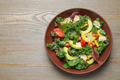 Tasty fresh kale salad on wooden table, top view. Space for text