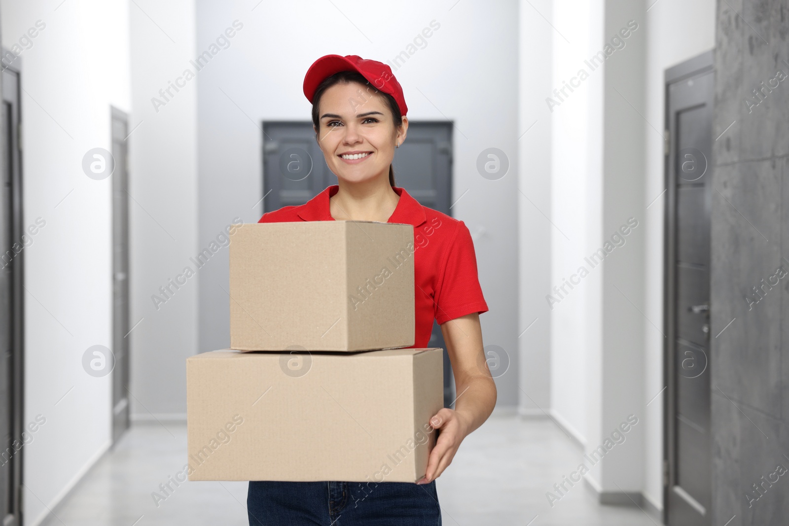 Photo of Smiling courier with cardboard boxes in hallway