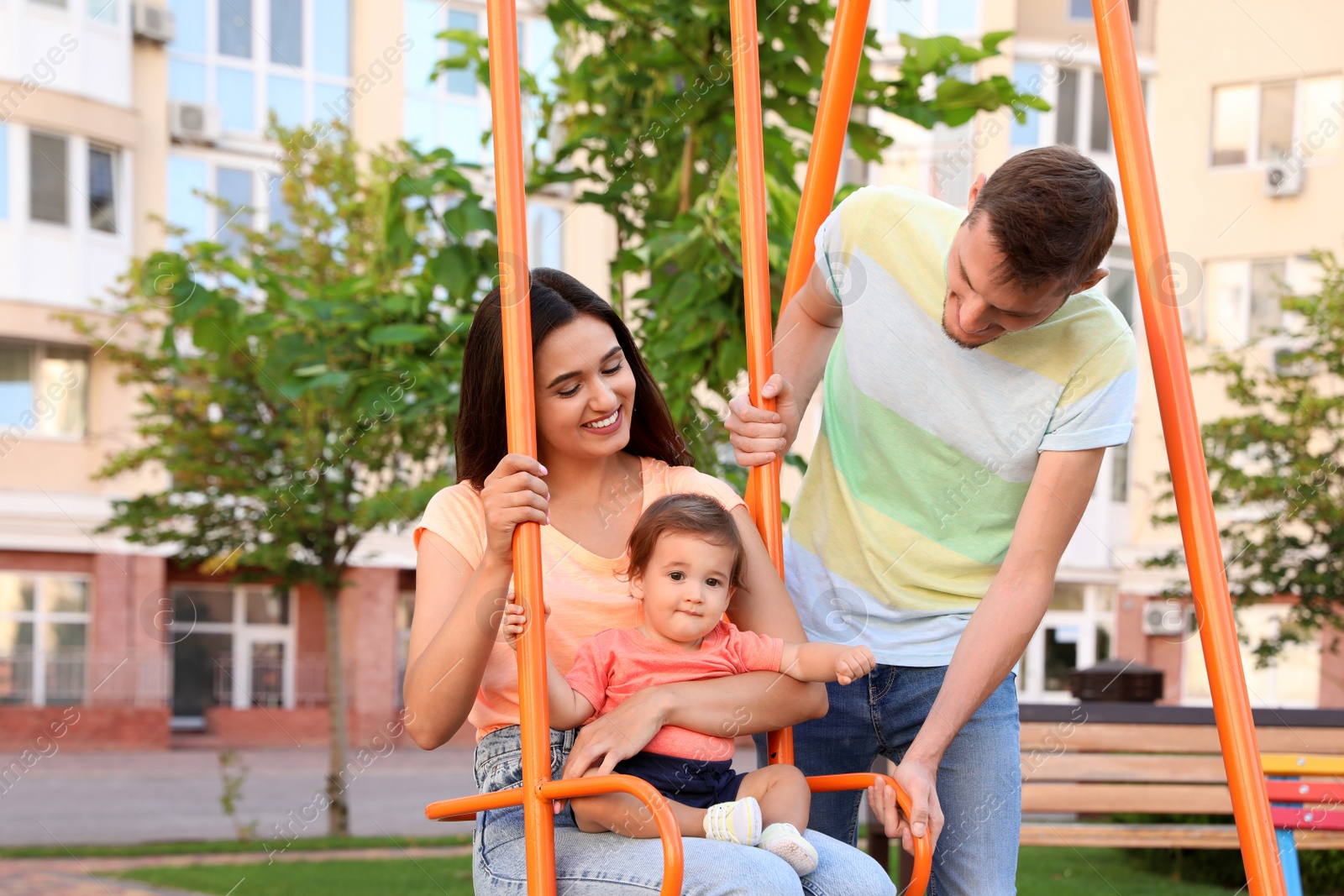 Photo of Happy family with adorable little baby at playground