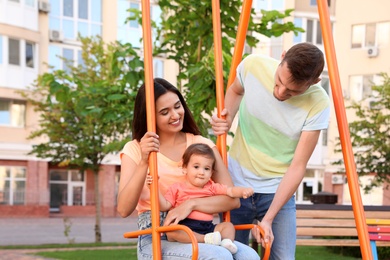 Happy family with adorable little baby at playground