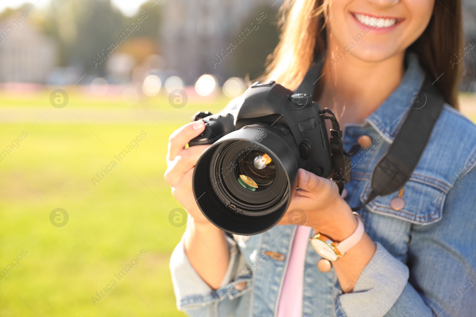 Photo of Young female photographer holding professional camera on street. Space for text