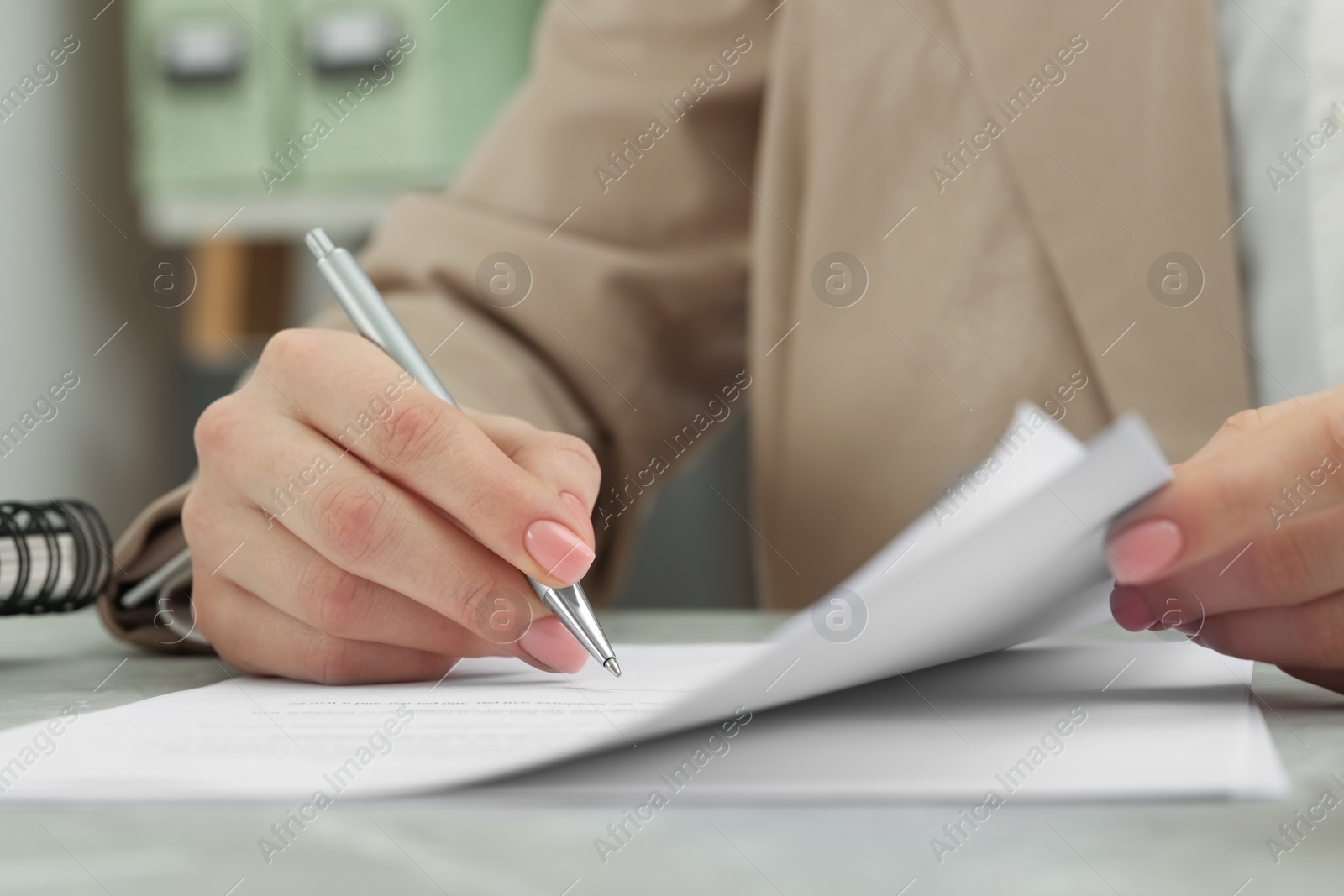 Photo of Woman signing document at table, closeup view