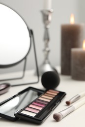 Photo of Mirror, cosmetic products and burning candles on dressing table, closeup