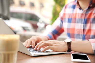 Young man working with laptop at desk, closeup