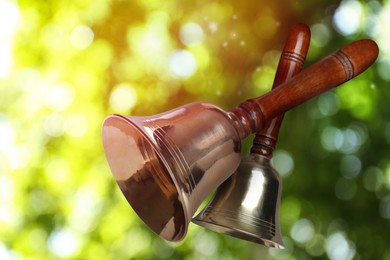 Image of Shiny school bells with wooden handle outdoors. Bokeh effect