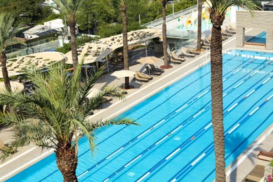 Photo of Outdoor swimming pool and tropical plants at luxury resort on sunny day