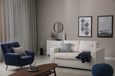 Stylish living room interior with white sofa, armchair and beautiful pictures