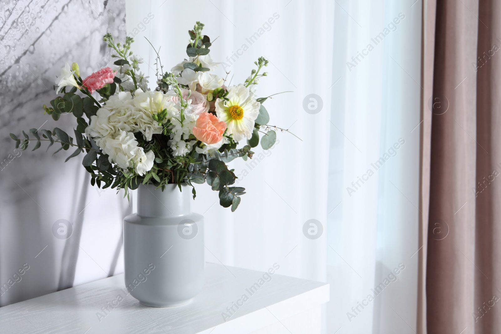 Photo of Bouquet with beautiful flowers on white chest of drawers indoors. Space for text