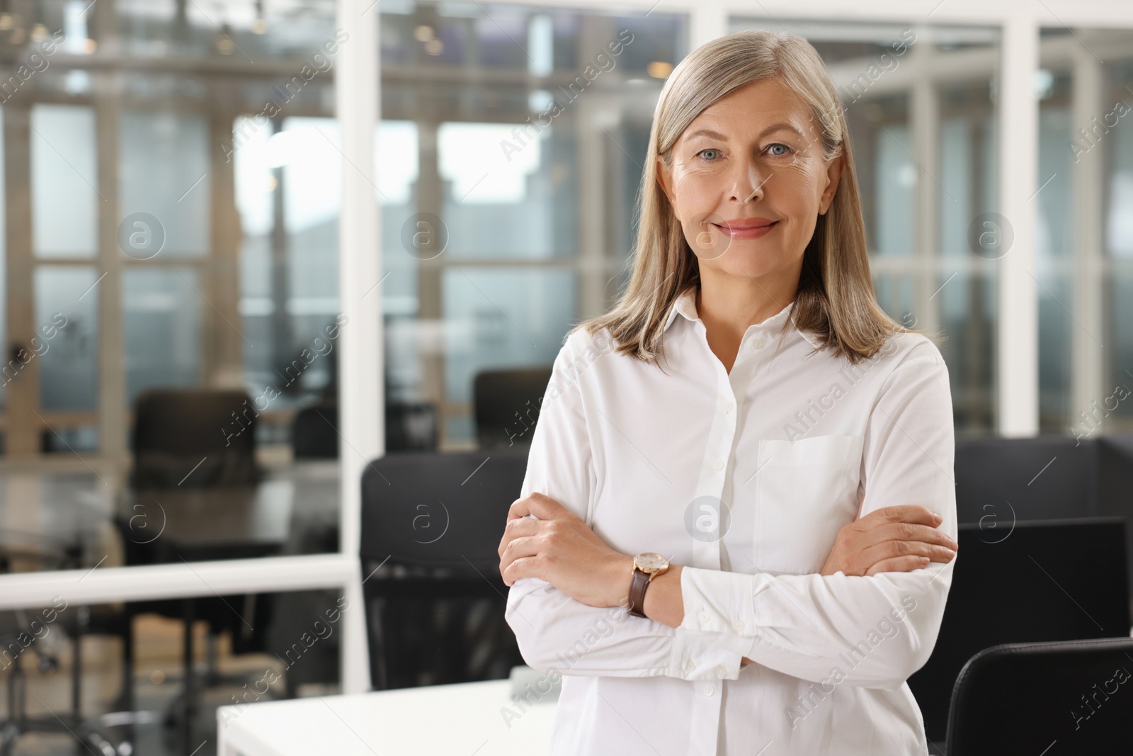 Photo of Confident woman with crossed arms in office, space for text. Lawyer, businesswoman, accountant or manager