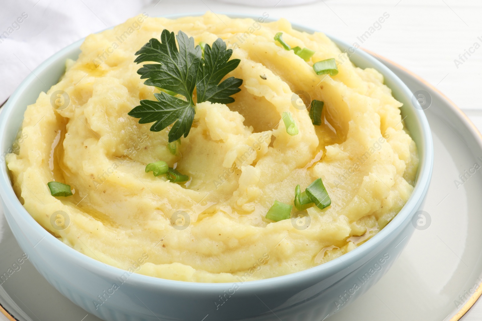 Photo of Bowl of tasty mashed potatoes with parsley and green onion on table, closeup