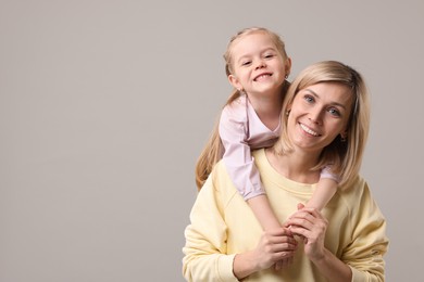 Family portrait of happy mother and daughter on grey background. Space for text
