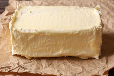 Photo of Piece of tasty homemade butter on parchment, closeup view