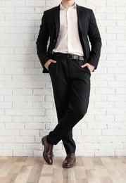 Photo of Man in elegant suit and leather shoes near brick wall