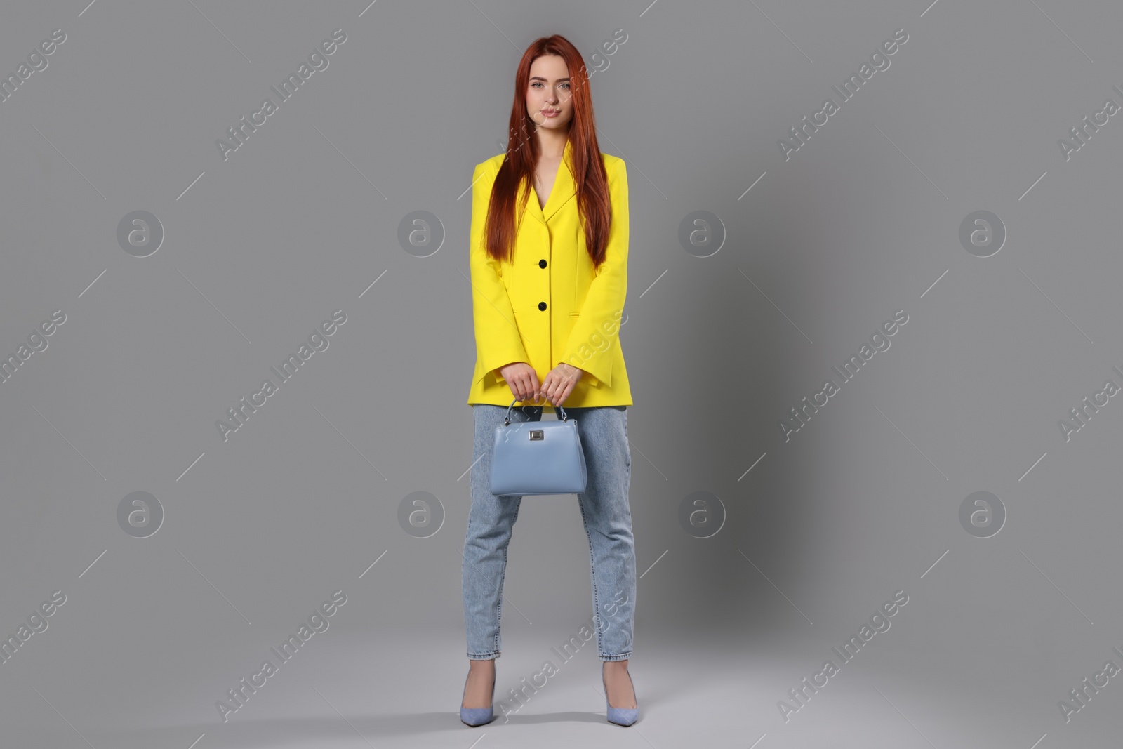 Photo of Stylish woman with red dyed hair and bag on light gray background