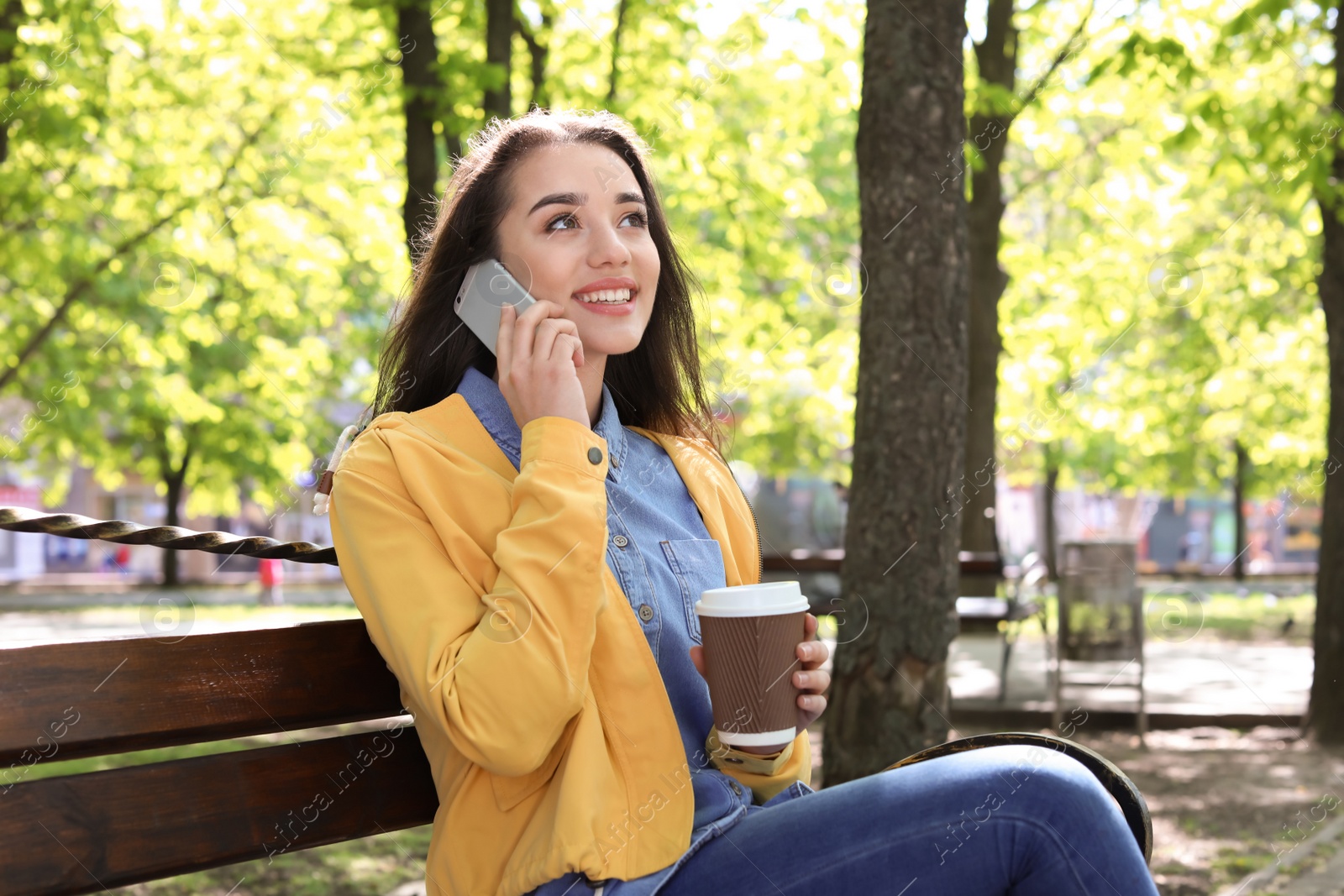 Photo of Young woman talking by phone outdoors on sunny day