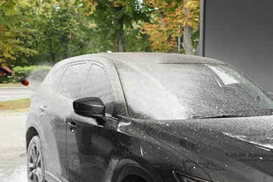 Photo of Man washing auto with high pressure water jet at outdoor car wash, closeup