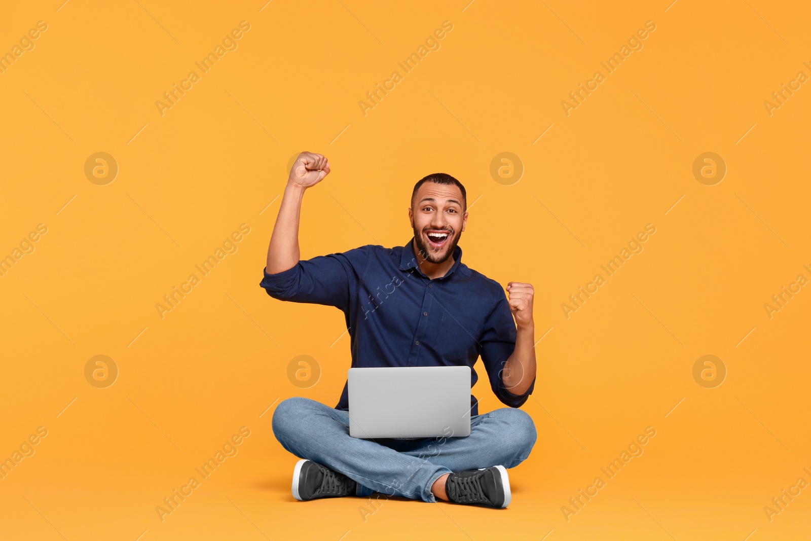 Photo of Happy young man with laptop on yellow background