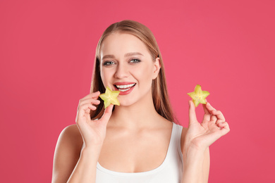 Young woman with cut carambola on pink background. Vitamin rich food