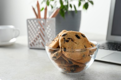 Photo of Chocolate chip cookies on light gray table at workplace