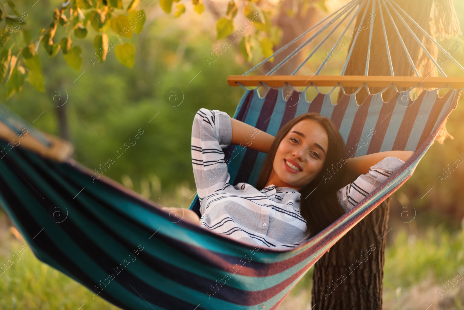 Photo of Young woman resting in comfortable hammock at green garden