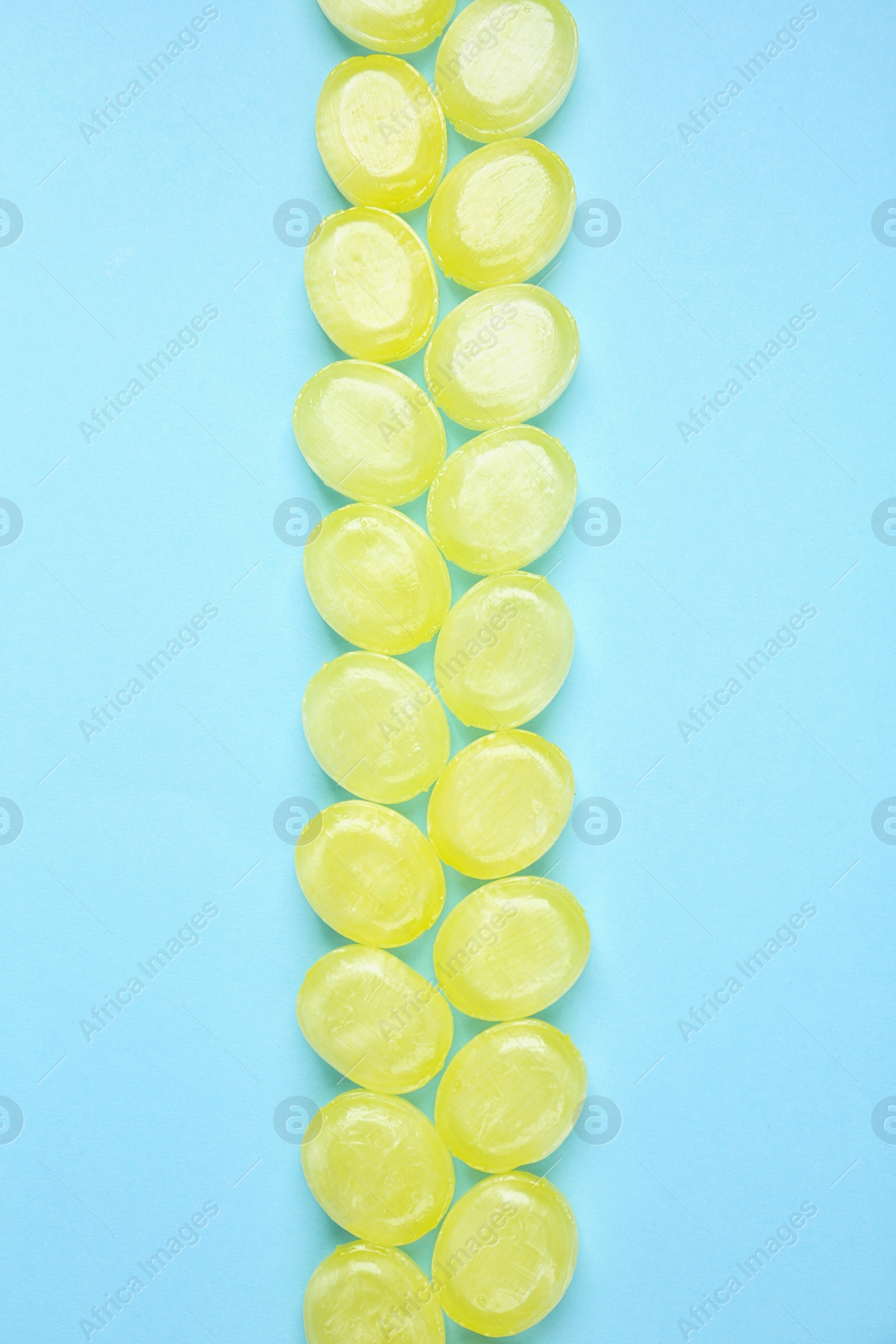 Photo of Many delicious lemon drops on light blue background, flat lay