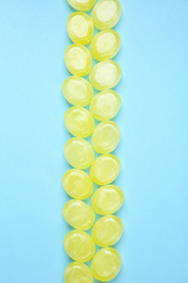 Photo of Many delicious lemon drops on light blue background, flat lay