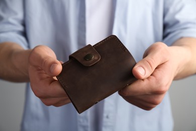 Photo of Man holding leather business card holder on grey background, closeup