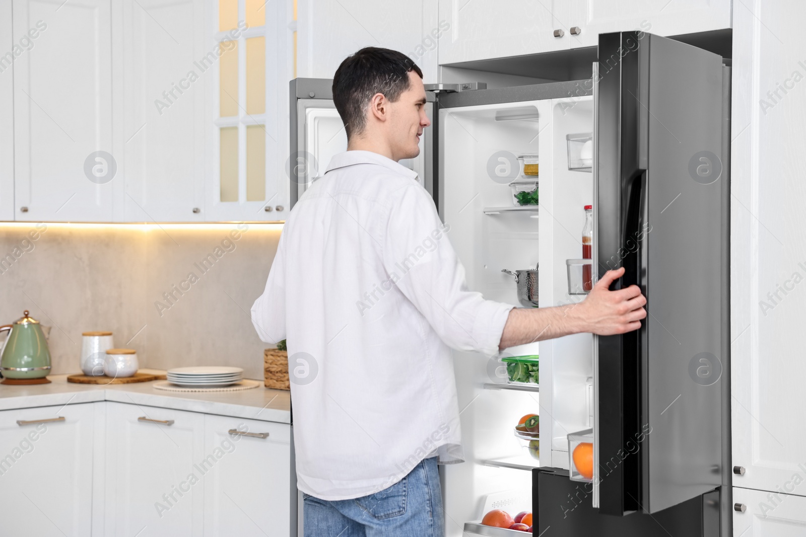 Photo of Happy man near refrigerator in kitchen at home