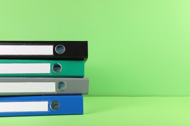 Stack of office folders on light green background, space for text