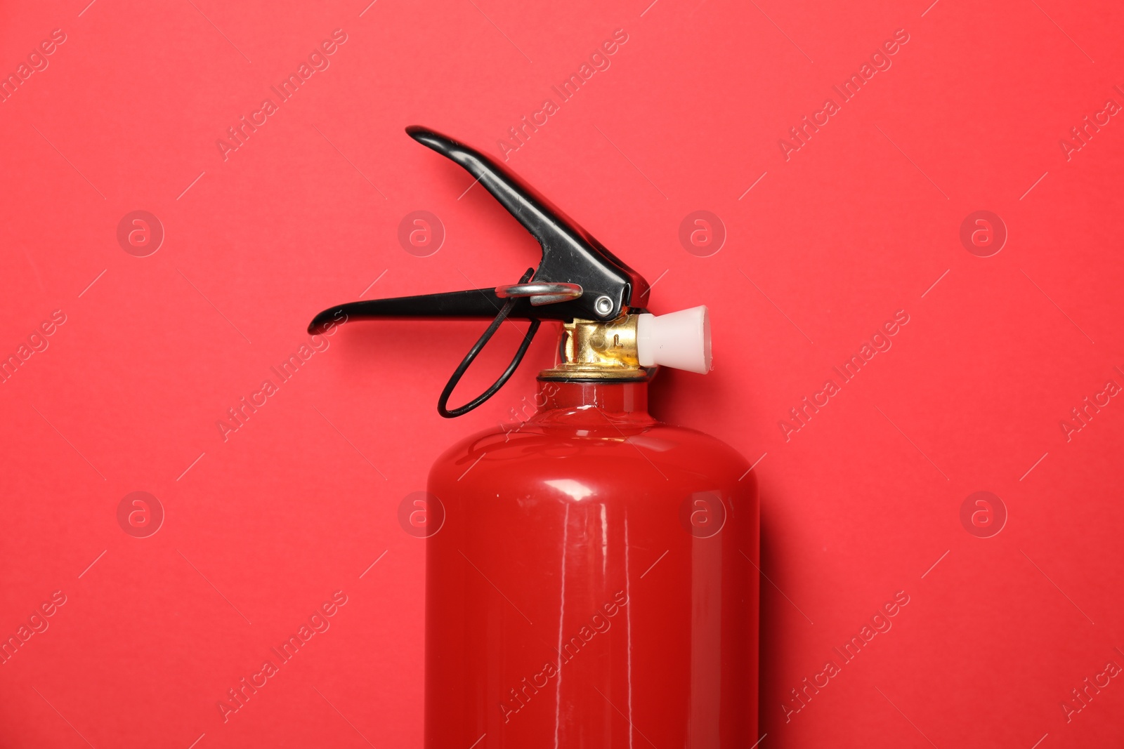 Photo of One fire extinguisher on red background, top view