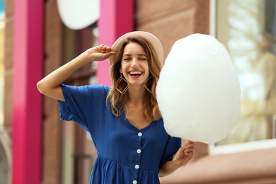 Photo of Happy young woman with cotton candy outdoors