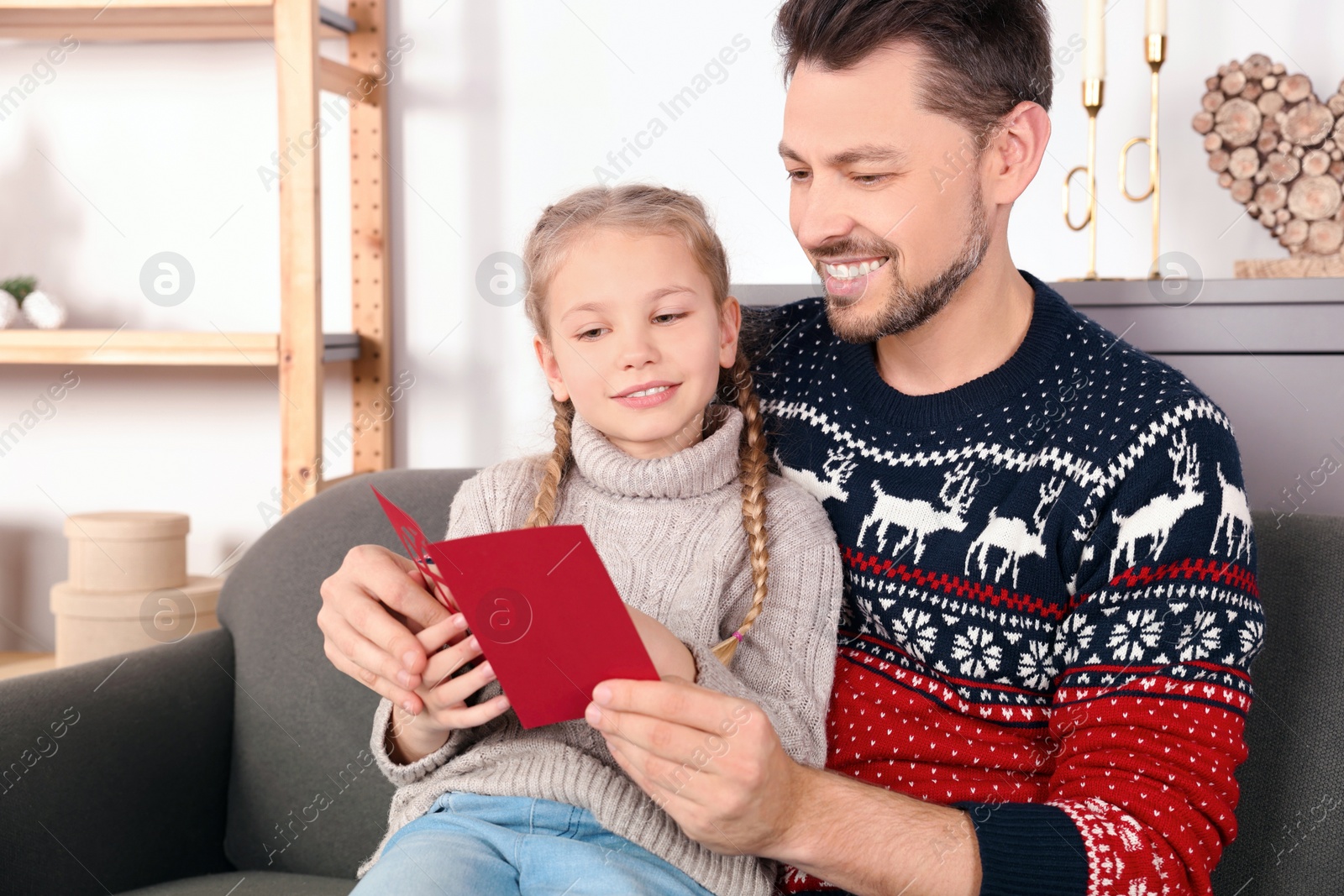 Photo of Happy man receiving greeting card from his daughter at home