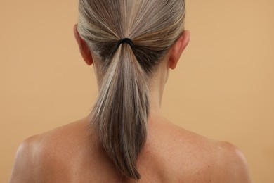 Mature woman with healthy skin on beige background, back view