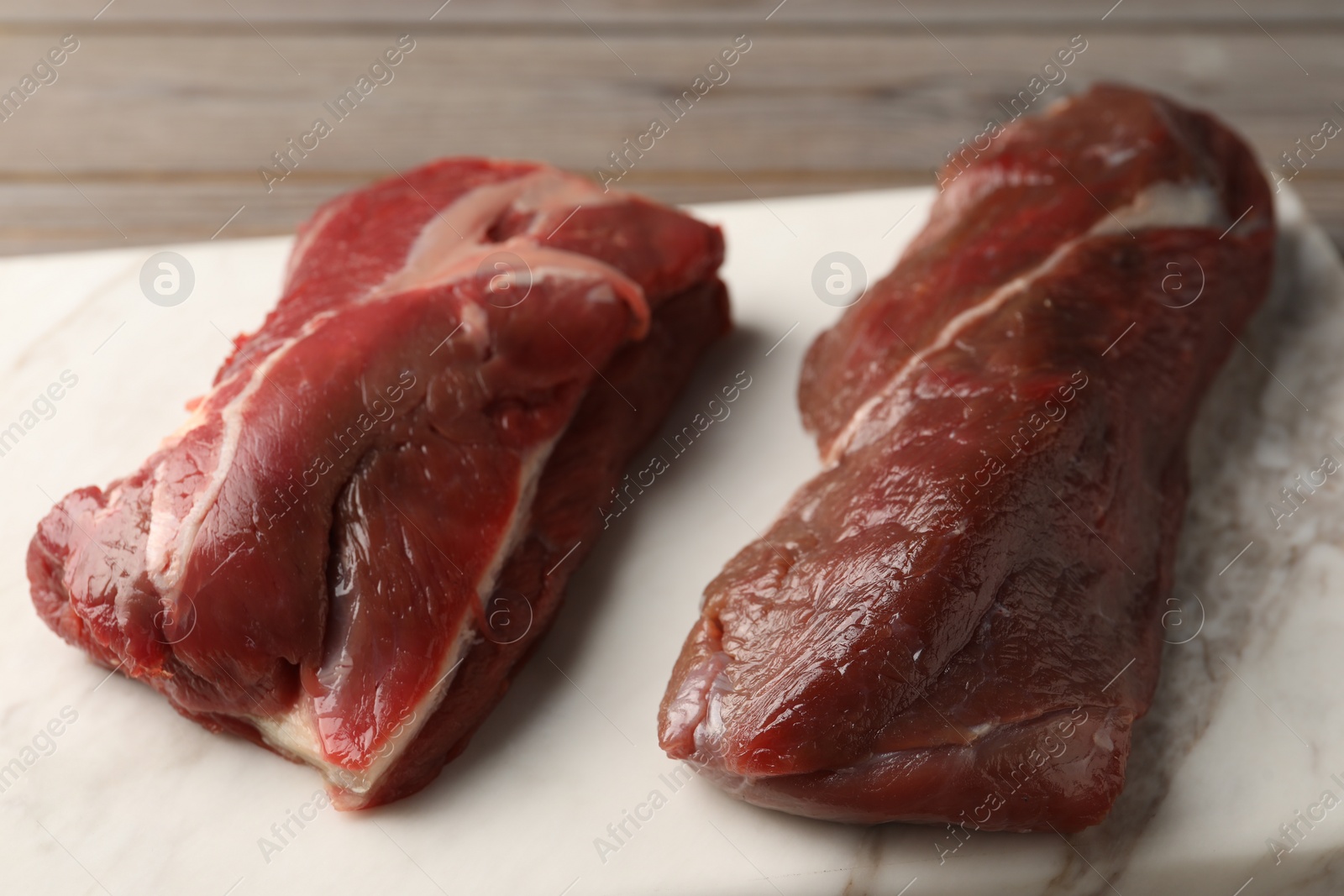 Photo of Pieces of raw beef meat on marble board, closeup