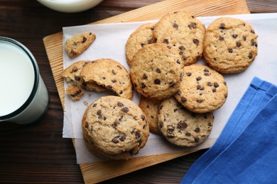 Photo of Delicious chocolate chip cookies and milk on wooden table, flat lay