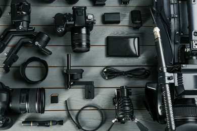 Photo of Flat lay composition with video camera and other equipment on grey wooden table