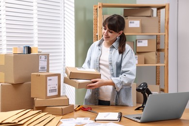 Photo of Parcel packing. Post office worker with parcels at wooden table indoors