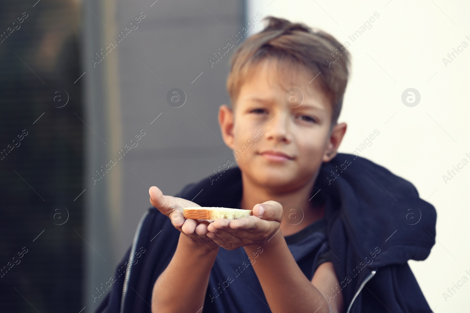 Photo of Poor little boy with bread on city street