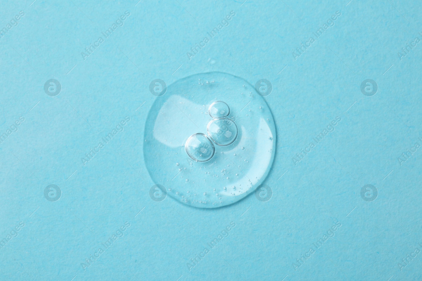 Photo of Sample of cosmetic serum on light blue background, top view