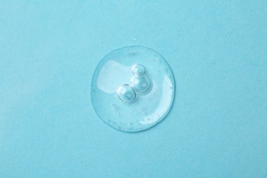 Sample of cosmetic serum on light blue background, top view