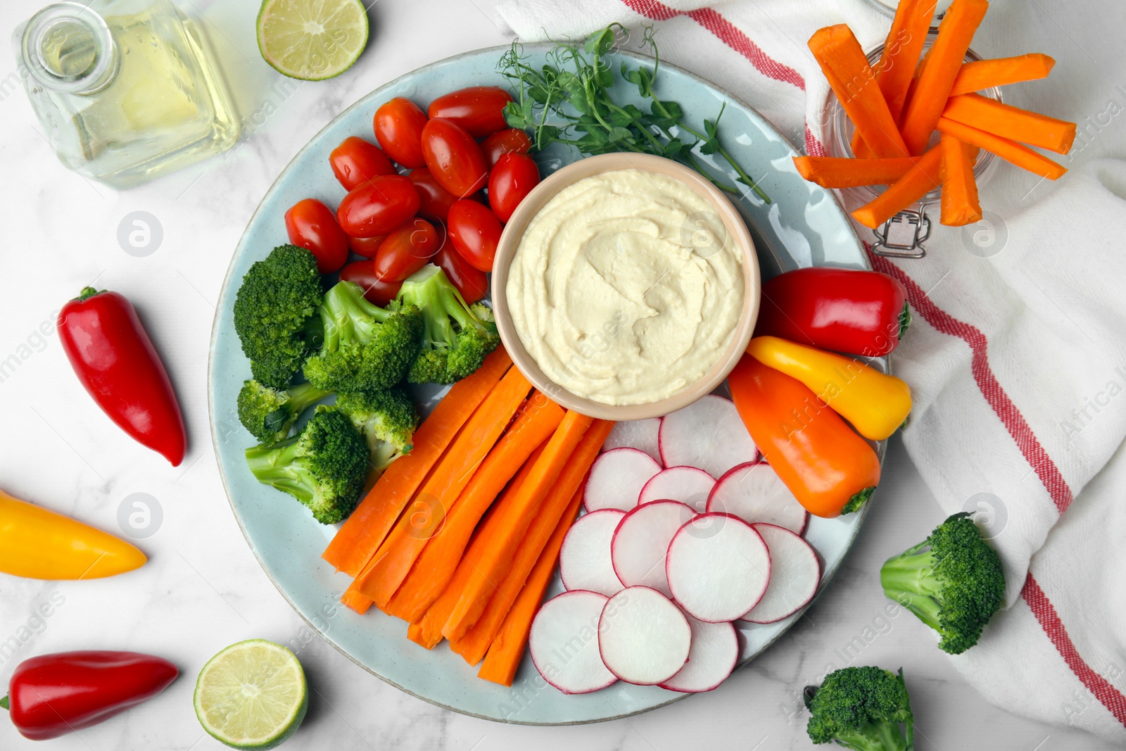 Photo of Plate with delicious hummus and fresh vegetables on white marble table, flat lay