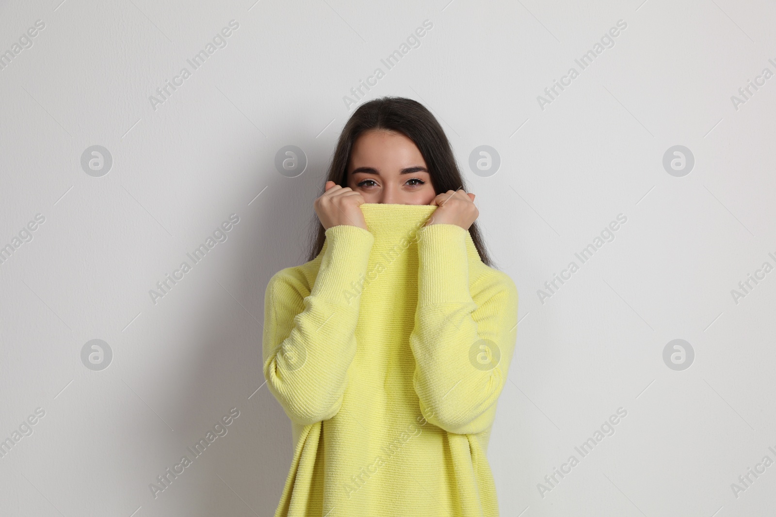 Photo of Beautiful young woman wearing yellow warm sweater on white background