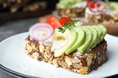 Photo of Plate with delicious avocado sandwich on grey table