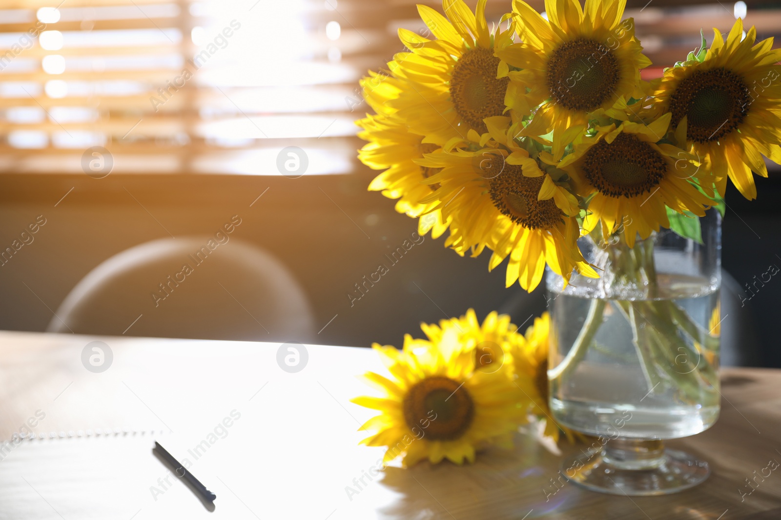 Photo of Bouquet of beautiful sunflowers on wooden table in room. Space for text