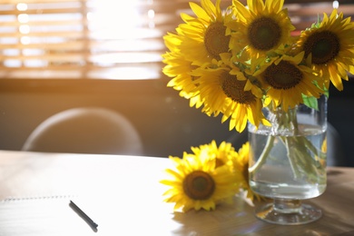 Bouquet of beautiful sunflowers on wooden table in room. Space for text