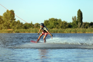 Photo of Teenage boy wakeboarding on river. Extreme water sport