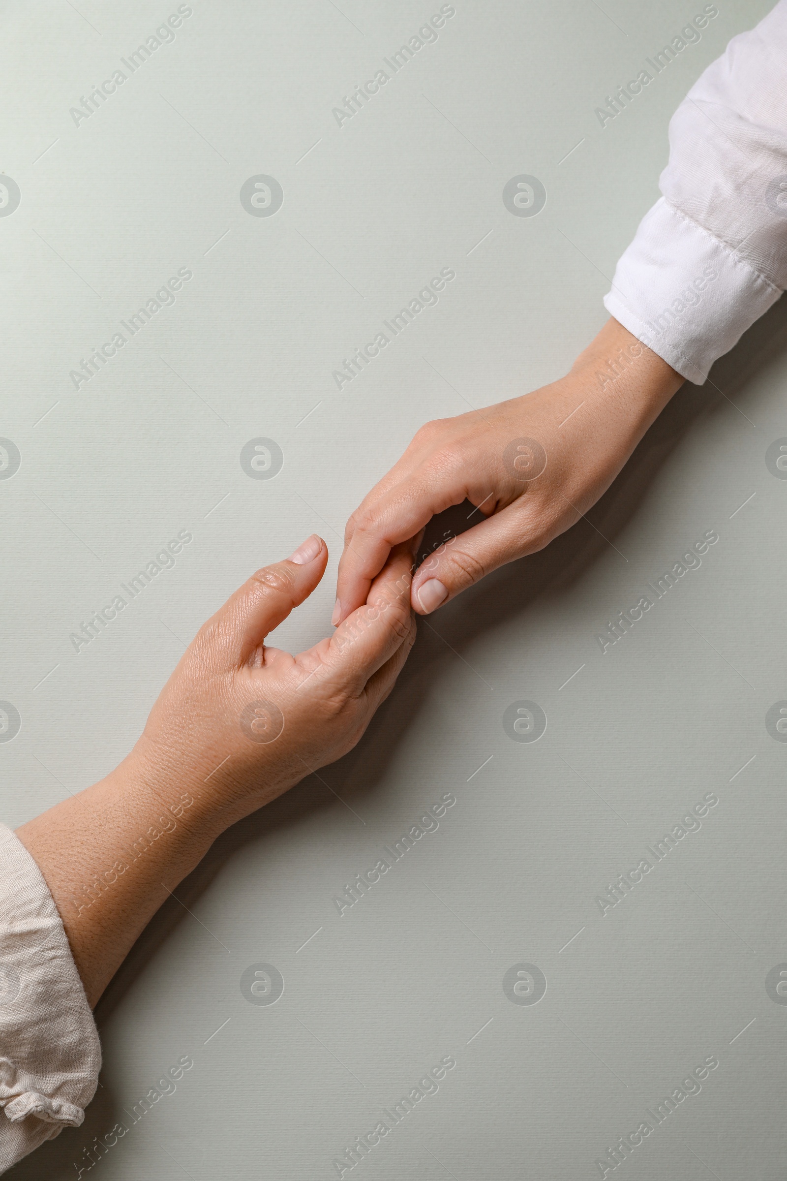 Photo of Woman holding hands with her mother light grey background, top view