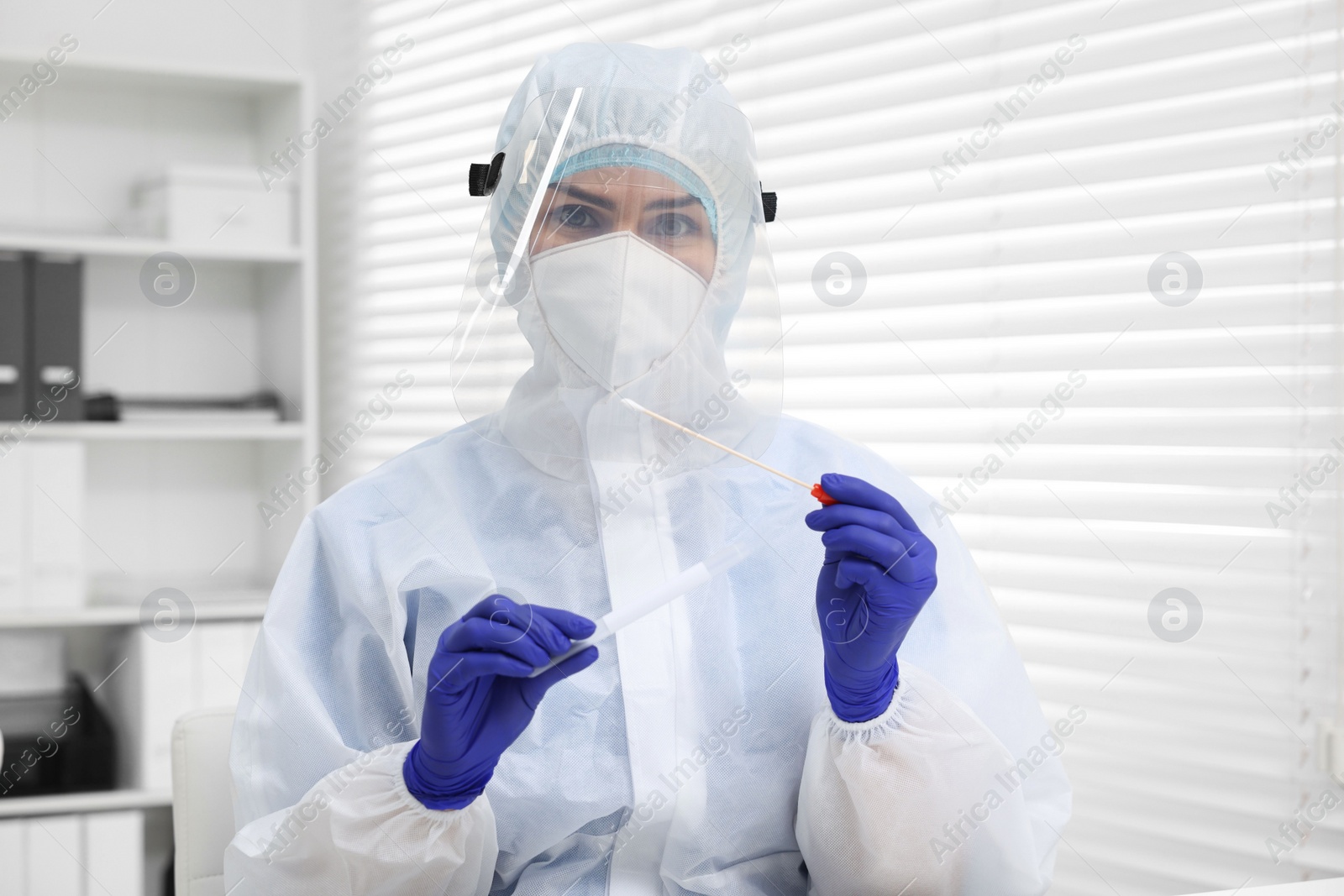 Photo of Laboratory testing. Doctor in uniform with cotton swab and tube at hospital